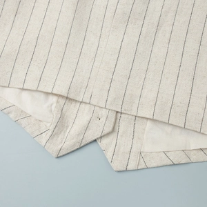 Detail of pinstriped vest hem showing cotton linen texture and professional stitching