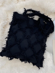 Retro black quilted canvas tote bag with fringe details on white plush background