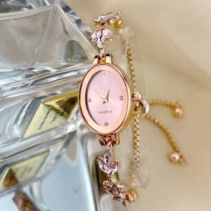 Detail of rose gold oval watch with pink dial and leaf-shaped diamond strap on silk