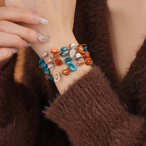 Detail view of multilayer bracelet with irregular orange and teal shell beads on model
