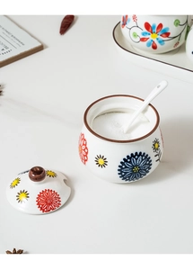 Detailed macro view of hand-painted ceramic condiment jar with floral pattern and spoon