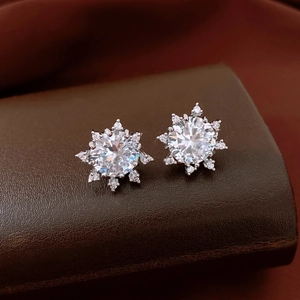 Detailed macro view of snowflake stud earrings with silver base and sparkling zircons