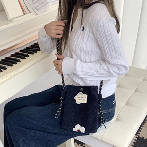 Close-up of black plush crossbody bag with white flower pattern and cord strap