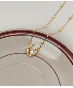 Macro shot of gold s925 silver necklace with twisted spiral pearl pendant on ceramic tray