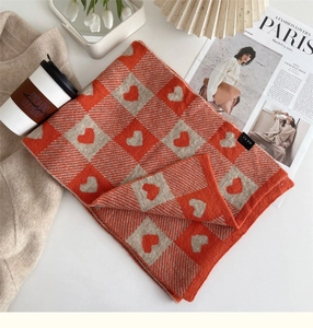 Detail of orange and beige checkerboard knit scarf with heart patterns and soft texture