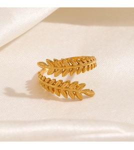 Détail de la bague ajustable en forme de feuille dorée sur un tissu en soie