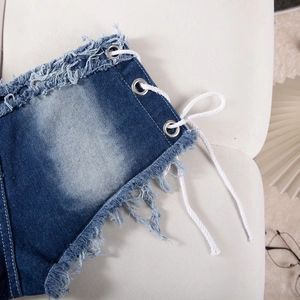 Dettaglio di pantaloncini in denim a vita bassa con lacci bianchi e bordi sfrangiati
