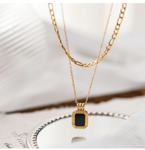 Detail of a gold double-layer necklace with a rectangular black onyx pendant on mirror