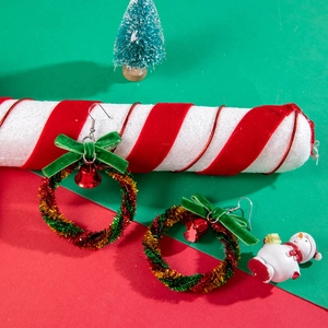 Detail of Christmas wreath earrings with velvet bows and bells on festive background