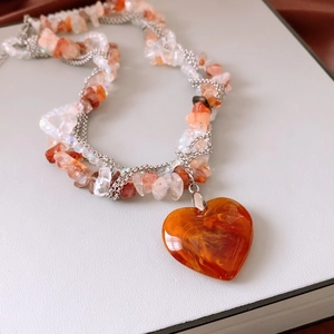 Macro view of multi-strand stone beads and orange heart pendant on a metal necklace