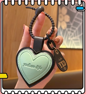 Detail of mint green heart leather keychain with black strap and decorative engraving