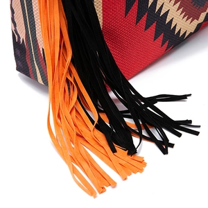 Detail of bohemian geometric woven fabric with vibrant orange and black suede fringe