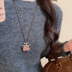Detailed view of leopard print cat paw pendant on brown braided leather cord