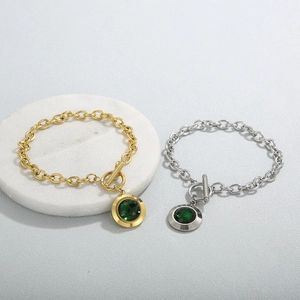 Détail de bracelets en or et argent avec pierre verte et fermoir à bascule en T élégant