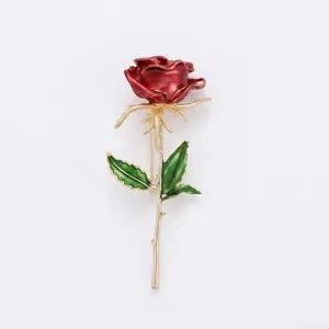 Elegant rose brooch with red enamel petals, green leaves, and golden long pin needle