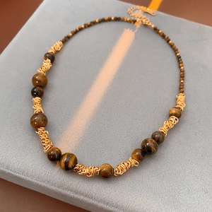 Détail des perles oeil de tigre et de l'enroulement de fil doré sur le collier