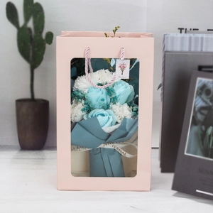 Close-up of blue rose and carnation soap bouquet in a pink windowed gift bag