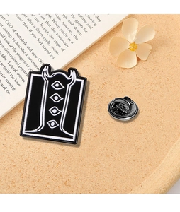 Detailed close-up of a black and white enamel alien pin with butterfly clutch