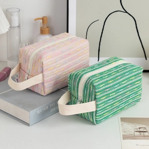 Detail of pink and green woven striped cosmetic bags with sturdy ribbon handles