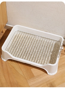 Detail of indoor dog potty with stainless steel mesh grid and pet litter on wood floor