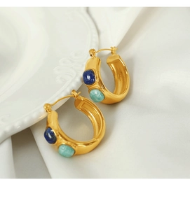 Macro view of C-shape 18k gold-plated hoops with blue and green gemstone inlay