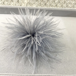 Macro detail of the fluffy grey ostrich feather brooch with soft natural textures