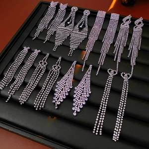 Détail de boucles d'oreilles à pompons violets avec strass sur présentoir en velours