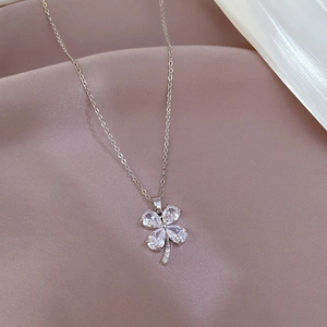 Macro detail of silver titanium clover pendant featuring four pear-cut zircons and fine chain