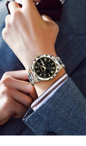 Detail of silver and gold quartz watch featuring dual calendar and black dial on wrist