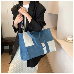 Detail of color-block denim tote bag showing striped detachable strap and patchwork design