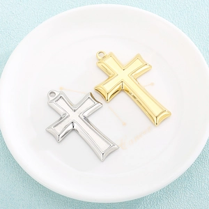 Polished gold and matte silver stainless steel cross pendants on a white ceramic plate