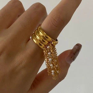Anello largo dorato multistrato con frange di perle bianche sulla mano