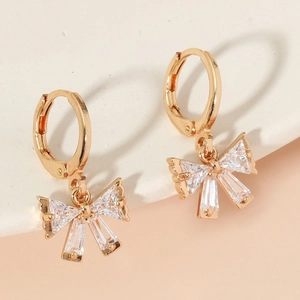 Golden butterfly hoop earrings with sparkling crystals on a modern aesthetic background
