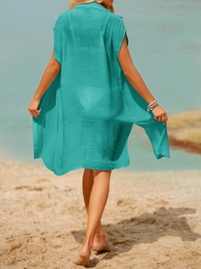 Back view of a turquoise long beach cover-up with textured fabric in a seaside setting