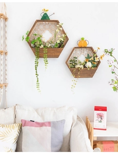 Detalle de dos maceteros de pared hexagonales de madera con celosía y plantas falsas