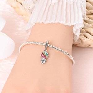 Detailed view of silver charm bracelet with a colorful lollipop pendant on a wrist