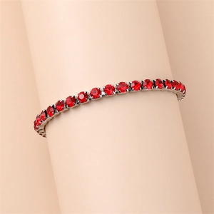 Close-up of silver tennis bracelet featuring round red crystals in a classic claw setting