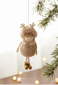Detail of plush Christmas angel doll with gold antlers hanging on a tree with bokeh light
