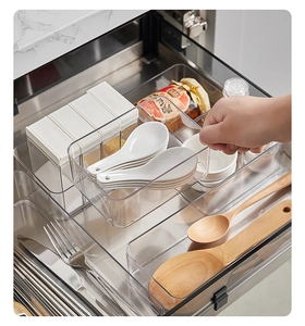 Close-up of a clear plastic kitchen drawer organizer being pulled out by hand