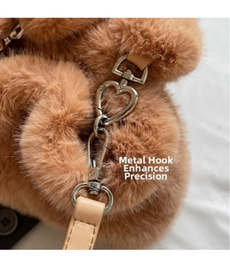 Detail of heart-shaped metal hook and leather strap on plush brown bucket bag