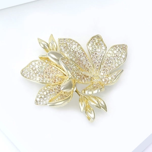 Macro shot of gold floral brooch with pavé-set cubic zirconia on plant leaf petals