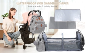 Grey multifunctional diaper bag converting into a portable travel bassinet with mesh sides