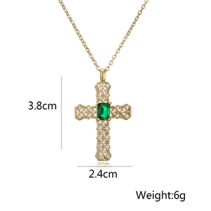 Macro shot of 18k gold plated cross pendant with green gem and zircon accents