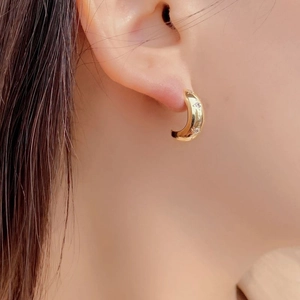 Detailed close-up of a gold-plated C-shaped hoop earring with three inlaid star accents