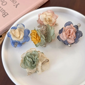 Five gradient fabric camellia flower hair claws on a white ceramic tray with pink book decor