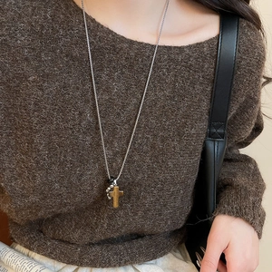 Detailed view of brown tiger eye cross pendant on a silver stainless steel chain necklace