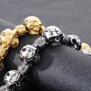 Punk style stainless steel skull bead bracelets in gold and silver finish on dark background