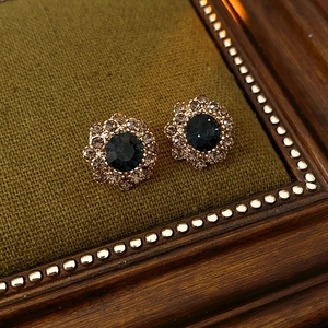 Gros plan de boucles d'oreilles fleur vintage en cristal bleu et métal doré sur velours