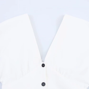 Minimalist white V-neck dress featuring contrasting black buttons and smooth woven fabric
