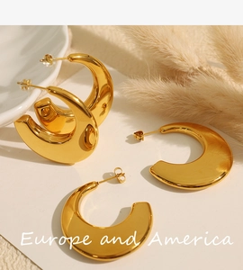 Detailed close-up of chunky C-shape gold-plated hoop earrings on a minimalist white tray